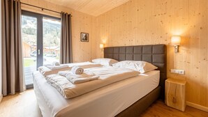 A bedroom with a large bed, wooden walls, and a view of a mountain landscape. - Pleasant Apartment With Sauna (Sankt Georgen am Kreischberg)