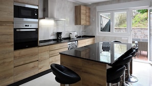 Eine moderne Küche mit Holzausstattung, Edelstahlgeräten und einer Bar mit Hockern.