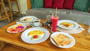 A breakfast table with plates of food, a glass of juice, and a coffee pot. - Sawitri Anandhita Luxury Villas (Ubud)