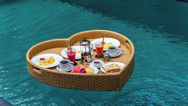 A floating breakfast tray with various food items and drinks over a pool. - Sawitri Anandhita Luxury Villas (Ubud)