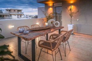 Una terrazza sul tetto con un tavolo di legno, sedie in vimini e piante in vaso.