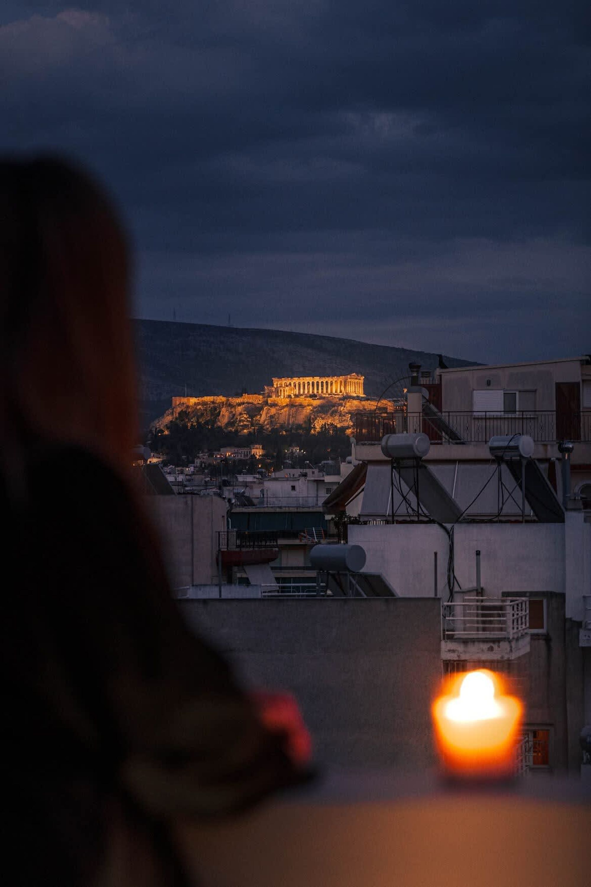 Une vue d’un bâtiment doté d’une structure imposante, situé sur une colline, qui pourrait être un site historique, entouré de bâtiments modernes et dont on aperçoit le toit, où se trouve du matériel.