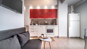 Una cocina moderna con armarios rojos, un refrigerador blanco y una pequeña mesa de comedor con un control remoto.