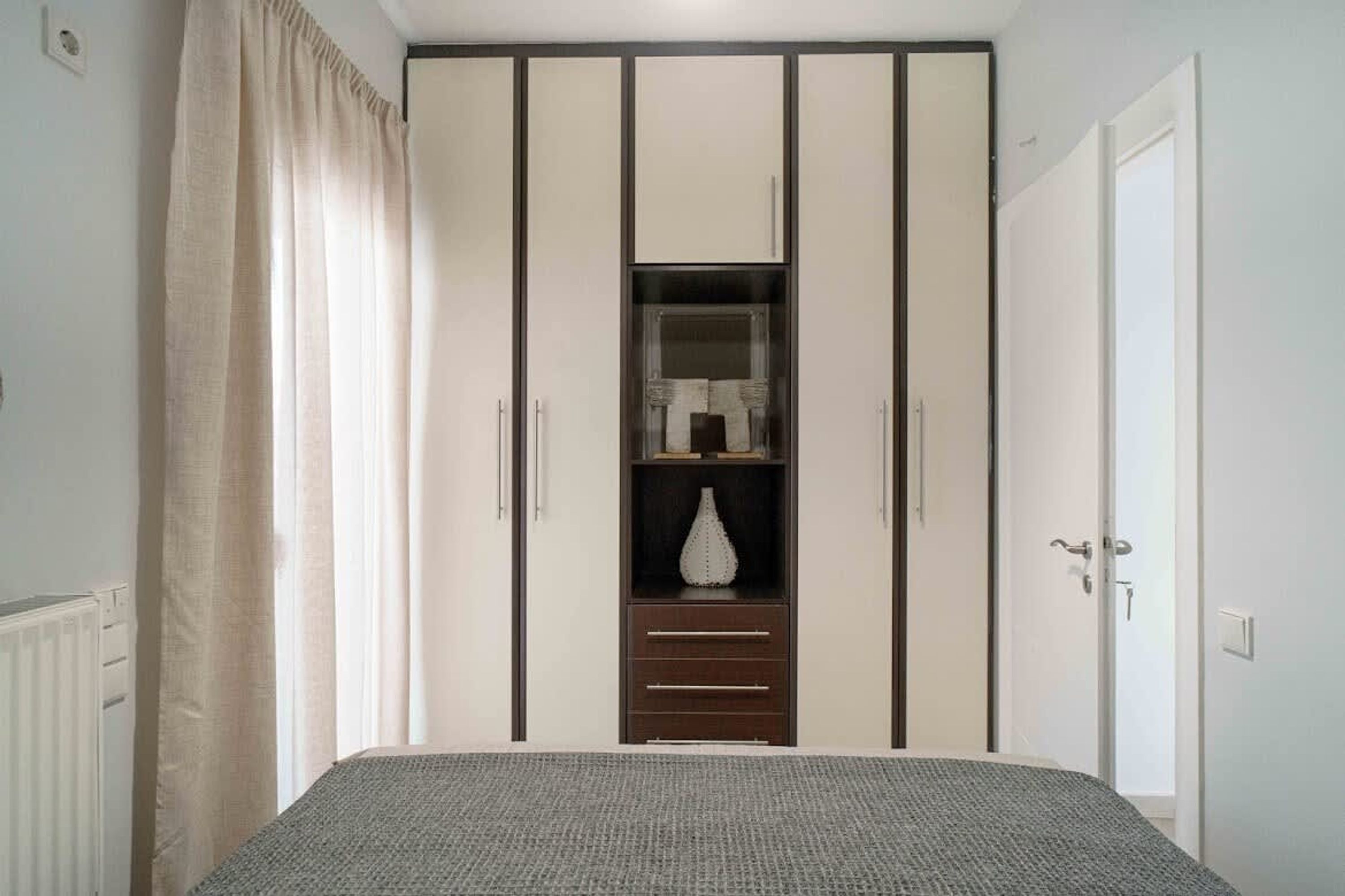 A bedroom with a bed, a wardrobe with a mirror, and a door.