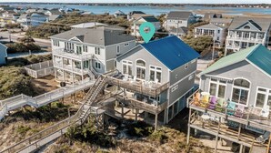 A coastal house with multiple decks and a staircase leading to the upper levels.