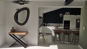 Una cocina moderna con armarios blancos, un salpicadero negro y una isla grande con taburetes de bar.