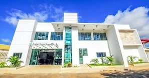 A modern building with a glass entrance, a sign reading 'Jardins Agua Azul', and a staircase leading to the entrance.