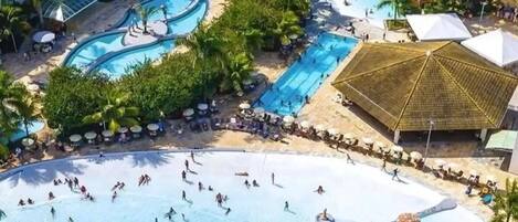 A resort with multiple swimming pools, palm trees, and a large covered area.