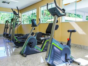 A row of stationary bikes in a gym with large windows and a tiled floor. - Ap Completo Parq. Aquát. Incrível Grátis (Caldas Novas)