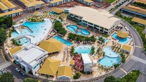 An aerial view of a resort with multiple swimming pools, a central building, and a roller coaster. - Ap Completo Parq. Aquát. Incrível Grátis (Caldas Novas)