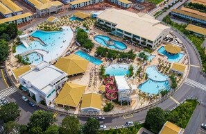 Une vue aérienne d’un complexe hôtelier comprenant plusieurs piscines, un bâtiment central et des montagnes russes.