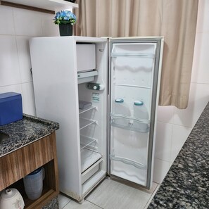 Une cuisine avec un réfrigérateur blanc, un plan de travail en granit et un meuble en bois.