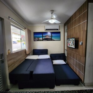 A room with a bed, a ceiling fan, an air conditioning unit, a window with curtains, and a wall-mounted TV. - Ap Completo Parq. Aquát. Incrível Grátis (Caldas Novas)
