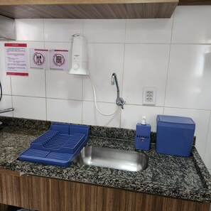 Une cuisine dotée d’un plan de travail en granit, d’un évier en acier inoxydable, d’un robinet, d’un distributeur de savon et d’un porte-savon bleu.