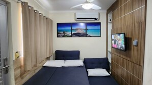 A room with a bed, a ceiling fan, an air conditioner, a TV, and a wooden wall. - Ap Completo Parq. Aquát. Incrível Grátis (Caldas Novas)