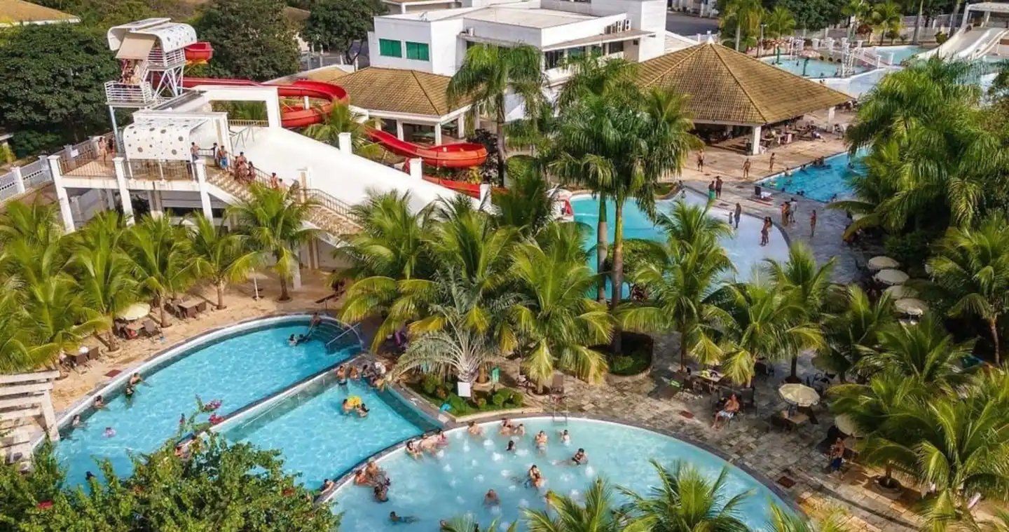 A resort with multiple swimming pools, palm trees, and a water slide.