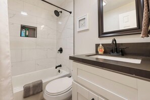 Ein Badezimmer mit Badewanne, Toilette und Waschbecken mit Spiegel darüber.