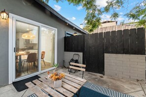 Eine Terrasse mit einem Holztisch und -stühlen, einem kleinen Blumentopf und einer Bank.
