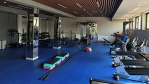Un gimnasio moderno con equipamiento de ejercicio, suelo azul y paneles de techo de madera.