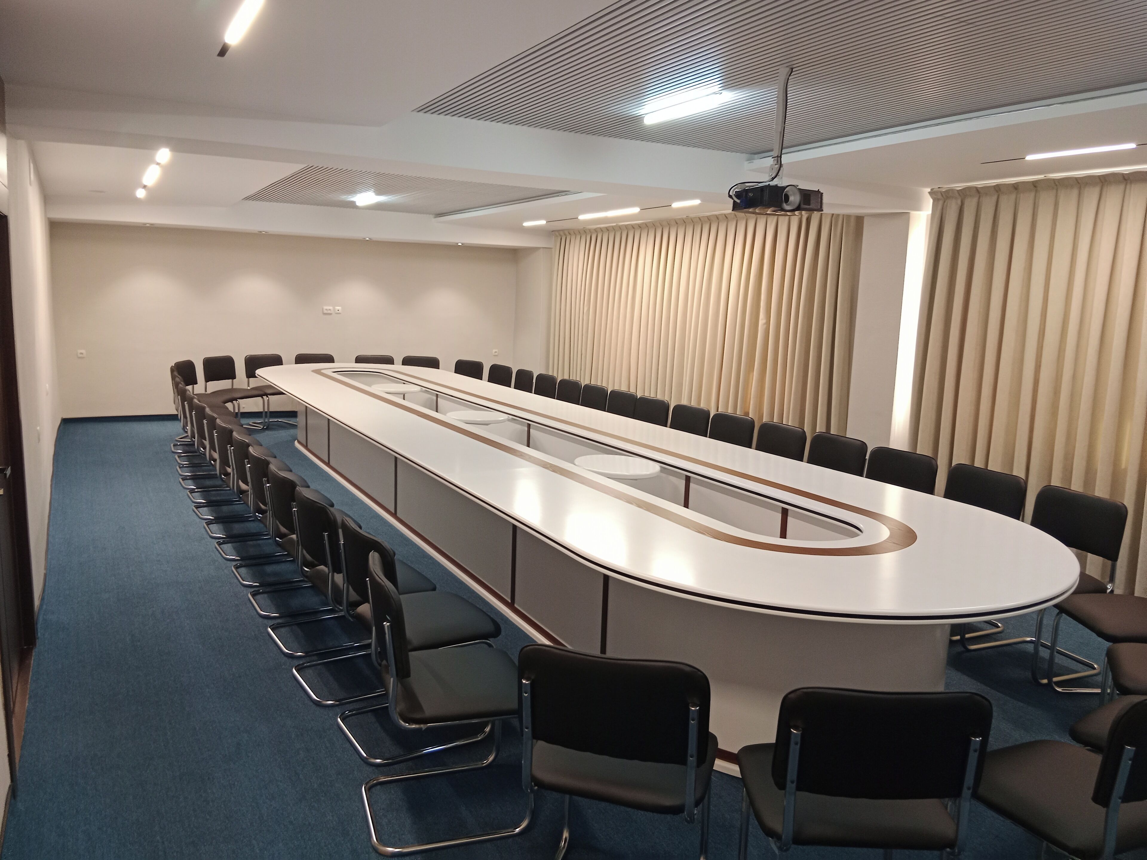 A conference room with a long table, chairs, and a projector.