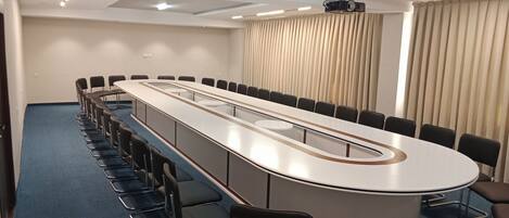 A conference room with a long table, chairs, and a projector.
