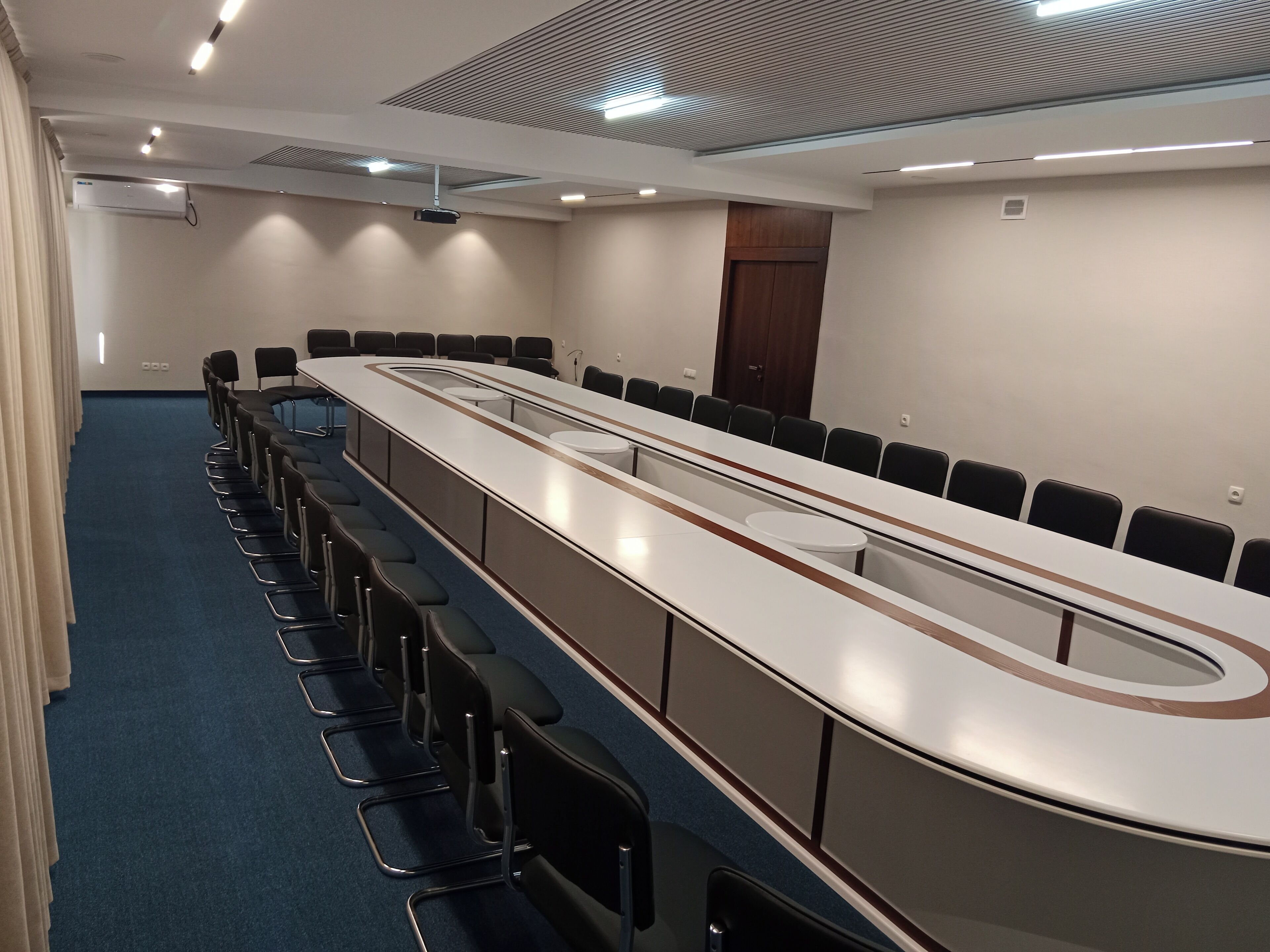 A conference room with a long table, chairs, and a projector.