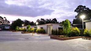 A parking lot with a building, trees, and street lamps. - Gallery Hotel Manjimup (Manjimup)