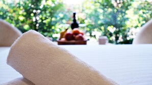 A white towel on a bed with a blurred background of greenery and a fruit bowl. - Gallery Hotel Manjimup (Manjimup)