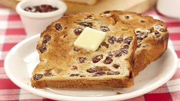 Two slices of bread with raisins and a pat of butter on a white plate.