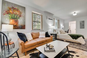 A modern living room with a sofa, coffee table, and a painting of flowers. - Private Porch! East ATL Stay Near Intl Soccer (Atlanta)