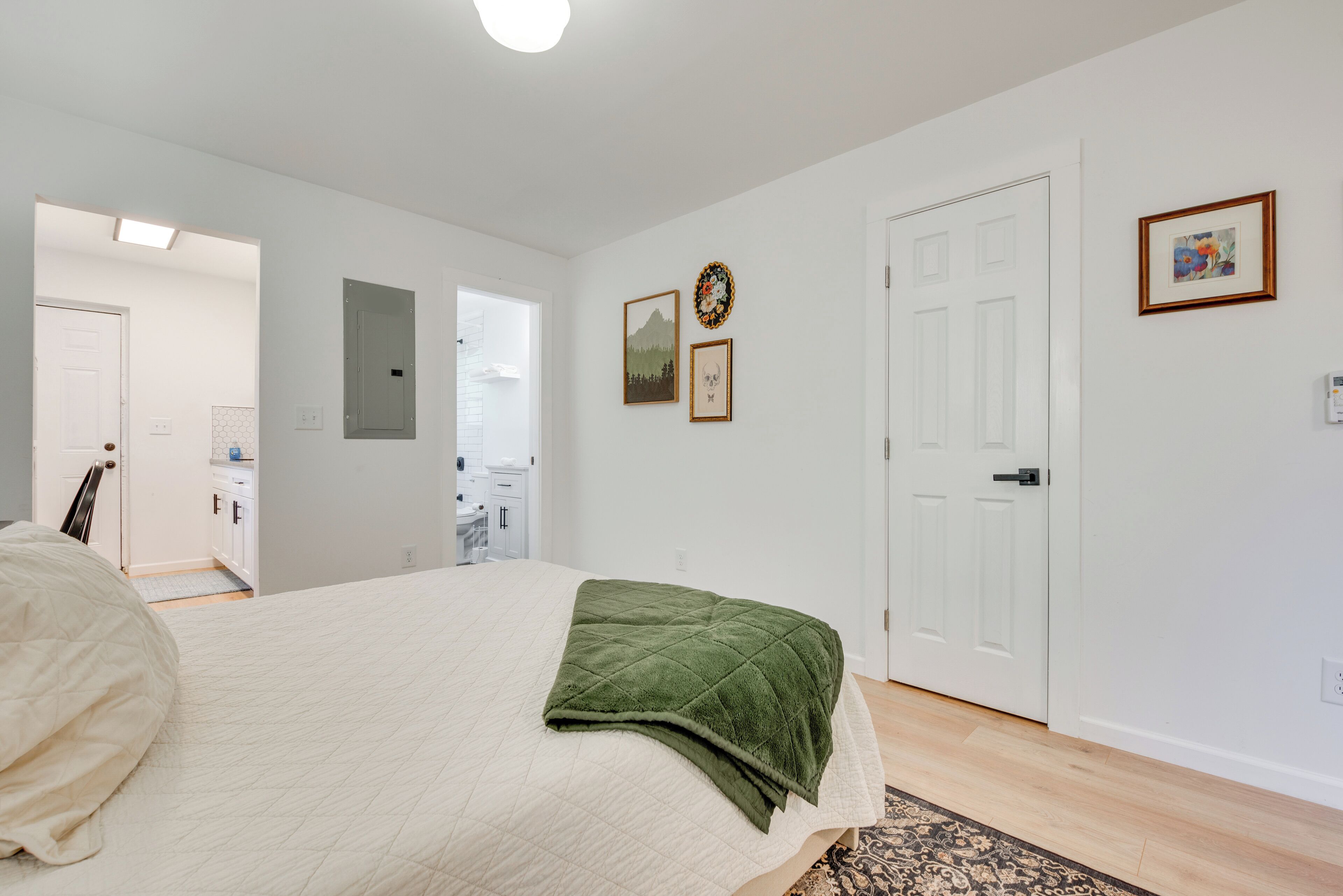 A bedroom with a bed, a door, and a wall with framed pictures.