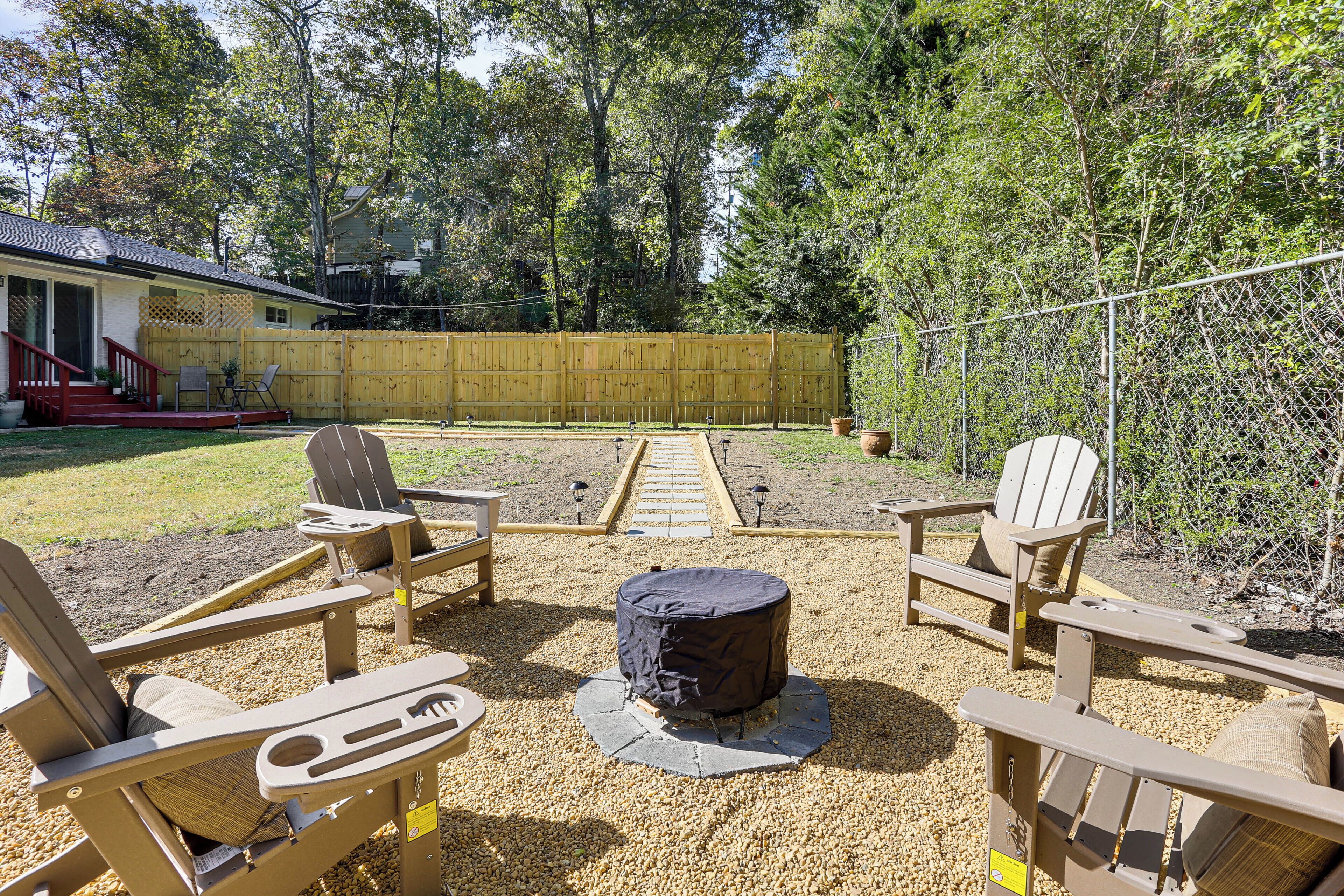 A backyard with Adirondack chairs, a fire pit, and a wooden fence.