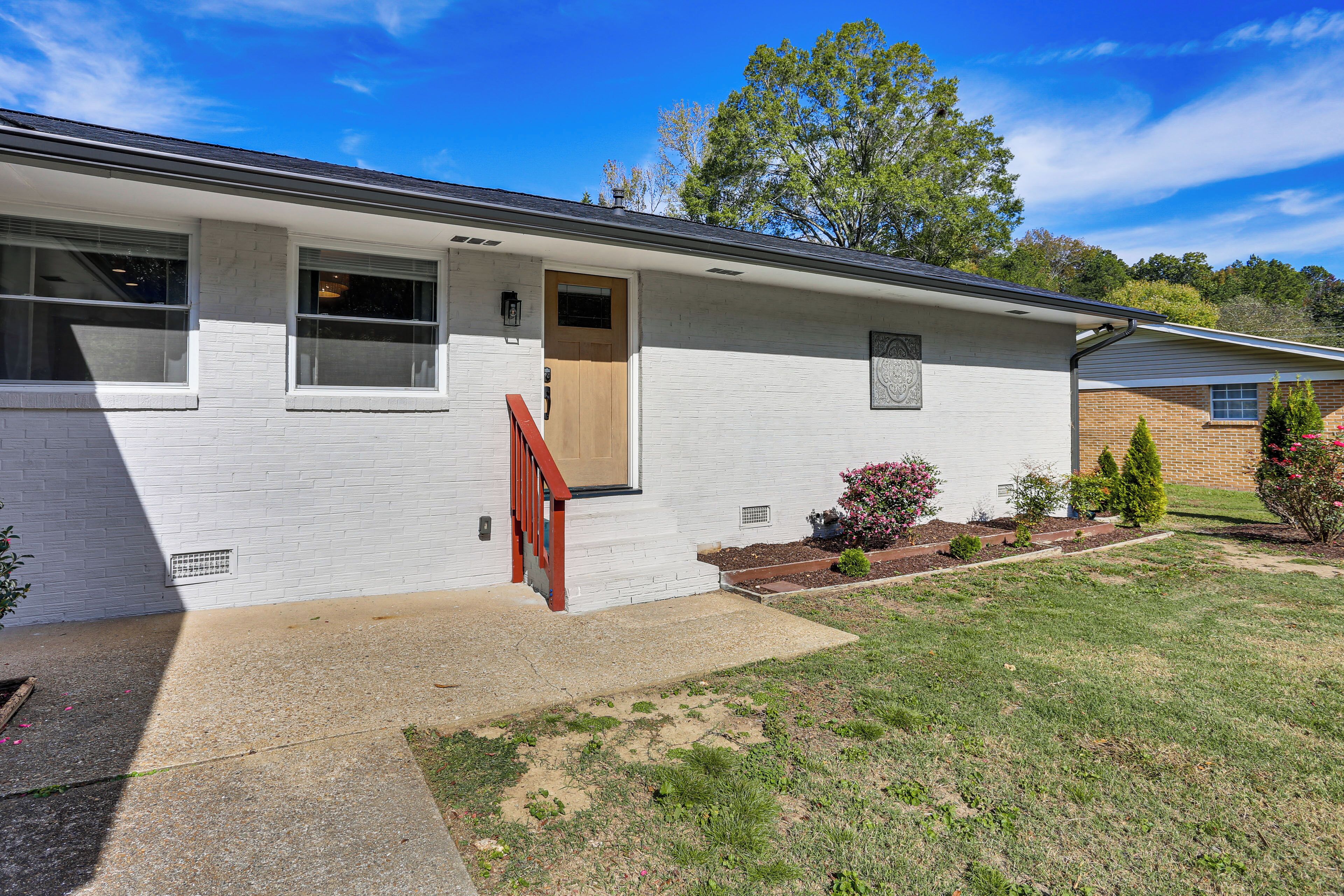 A single-story house with a front door, a small porch, and a well-maintained lawn.