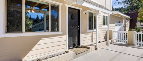 A residential house with a front porch, a black front door, and a small entryway.