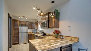 A modern kitchen with wooden cabinets, stainless steel appliances, and a wooden island with bar stools. - Mtn-view Gem w/ Grill: 2 Mi to Dtwn Livingston (Livingston)