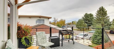 Eine Terrasse mit Gartenmöbeln, einem Grill und Blick auf eine Wohngegend.