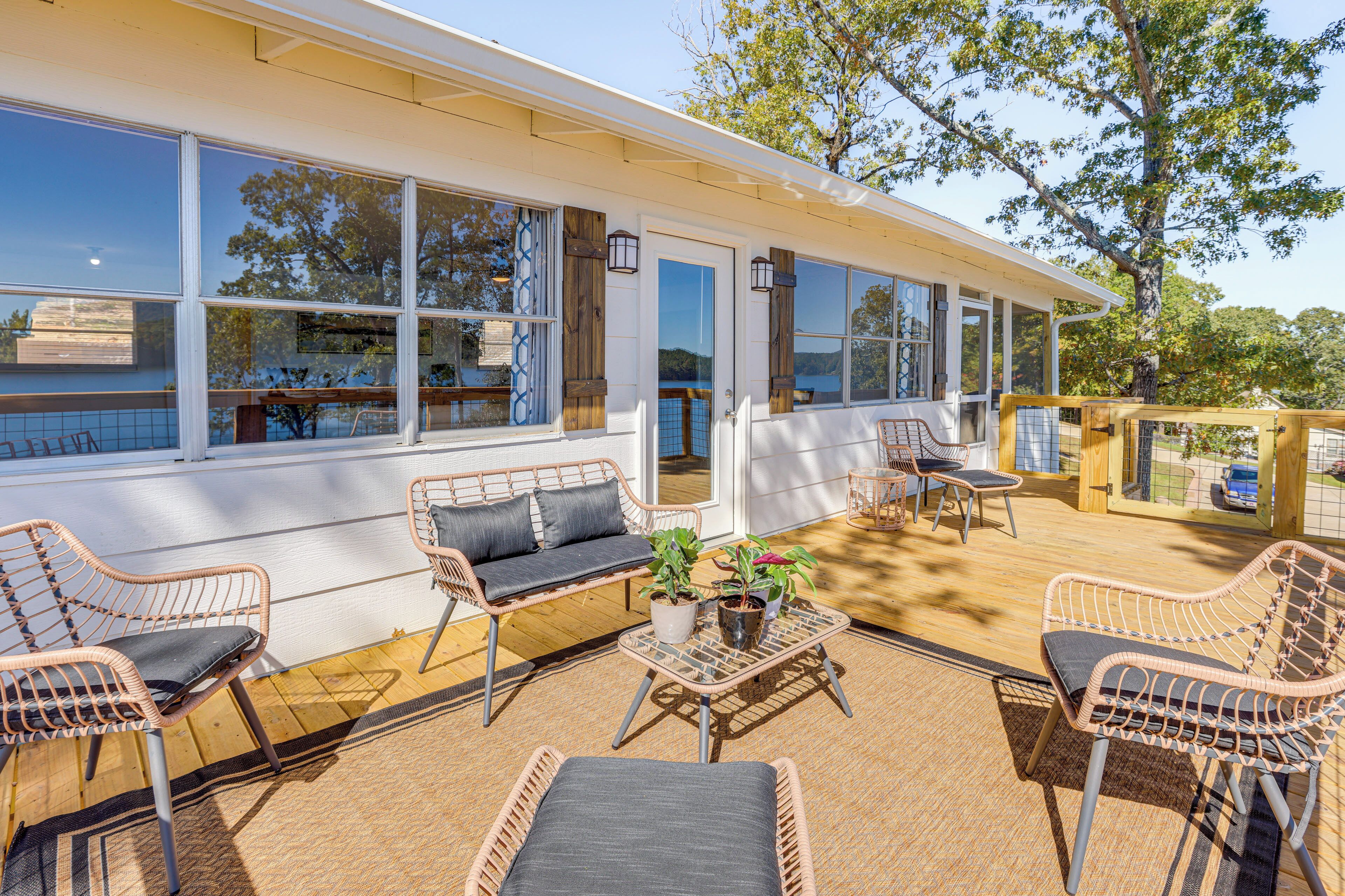 A covered outdoor area with wicker furniture, potted plants, and a view of the surrounding landscape.