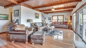 Een ruime woonkamer met lederen meubels, houten vloeren en een hoge plafond met zichtbare balken.