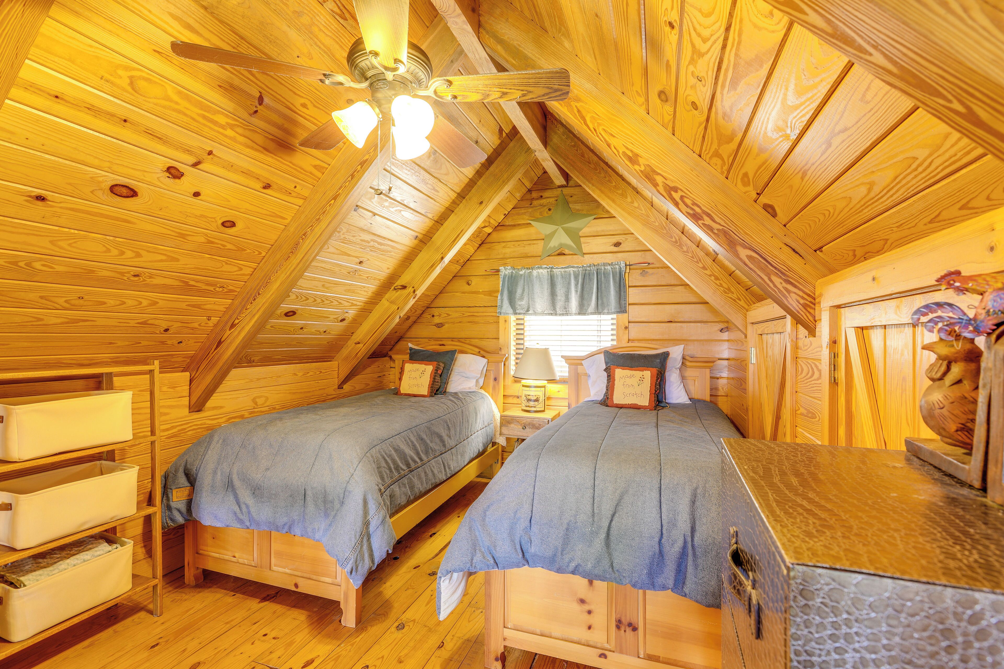 A cozy attic bedroom with two wooden beds, a ceiling fan, and a star decoration.