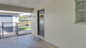 A clean, modern entrance with a grey door, a welcome mat, and a fenced driveway leading to a garage.