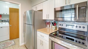 A kitchen with white cabinets, stainless steel appliances, and a microwave.