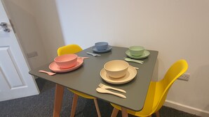 A small dining table with colorful plates and cutlery, surrounded by yellow chairs. - Luxury 2 bed Flat in Leicester (Leicester)
