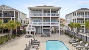A multi-story hotel with a pool area, outdoor seating, and a bar. - Carolina Kai, 7 Bedroom, Second Row w/ Private pool & Elevator (Ocean Isle Beach)