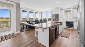 A modern kitchen with a large island, built-in appliances, and a view of the outdoors. - Carolina Kai, 7 Bedroom, Second Row w/ Private pool & Elevator (Ocean Isle Beach)