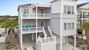 A two-story beachfront house with a balcony, a staircase, and a view of the ocean. - Carolina Kai, 7 Bedroom, Second Row w/ Private pool & Elevator (Ocean Isle Beach)