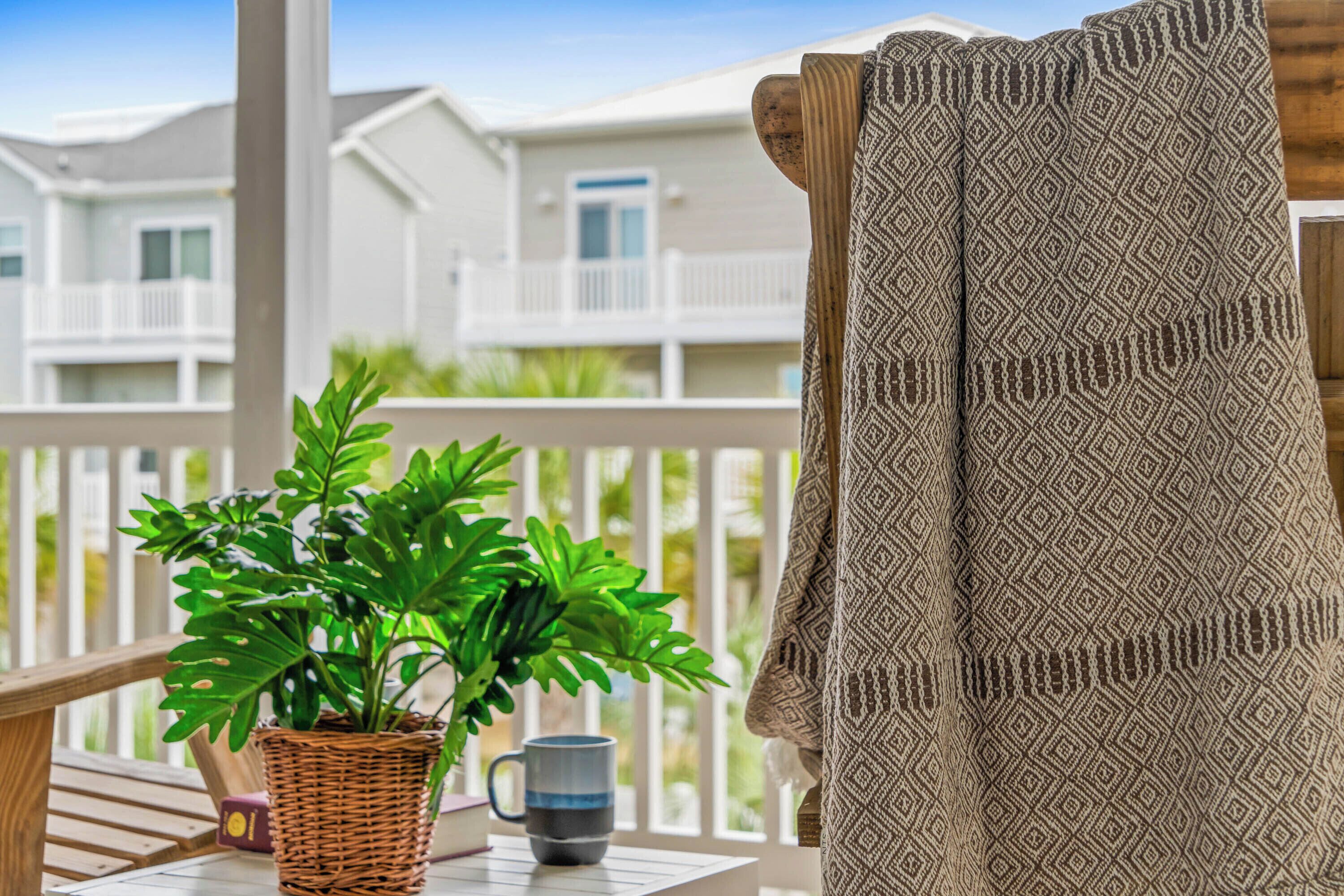 A balcony with a wicker plant pot, a mug, and a patterned cloth.