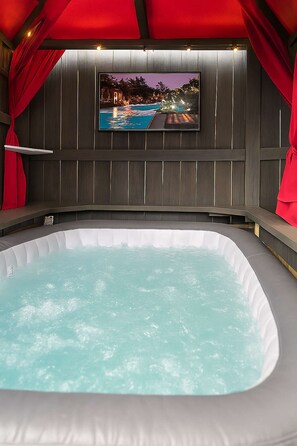 A hot tub with a television screen above it displaying a beach scene.