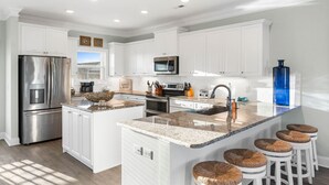 A modern kitchen with white cabinetry, stainless steel appliances, and a granite countertop. - Easy Breezy is a 4 bedroom, 5 bathroom house w/ private pool & elevator (Sunset Beach)