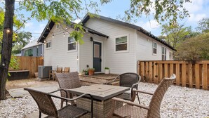 A house with a patio area featuring wicker furniture and a table.