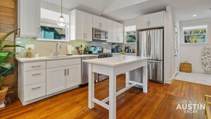 A modern kitchen with white cabinetry, stainless steel appliances, and a wooden floor.